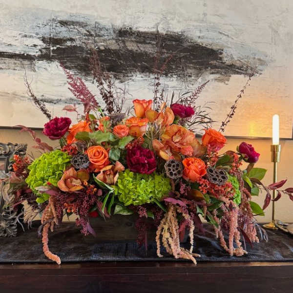 Large floral centerpiece with orange and magenta blooms in a low container