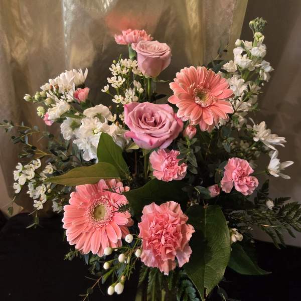 Pink roses and gerbera daisies with white filler flowers in a bouquet