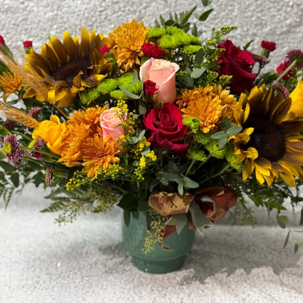 Mixed bouquet with sunflowers, roses, and mums in a green vase