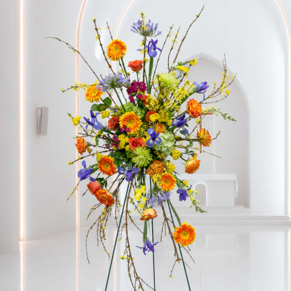 Tall mixed flower arrangement with orange, purple, yellow, and green blooms