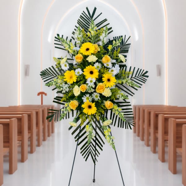 Yellow and white floral standing spray on an easel in a church aisle
