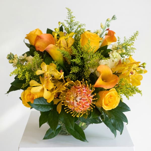 Yellow and orange floral arrangement in a glass vase