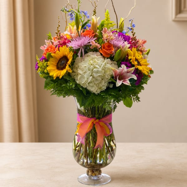 Colorful mixed bouquet in a clear glass vase with a ribbon bow