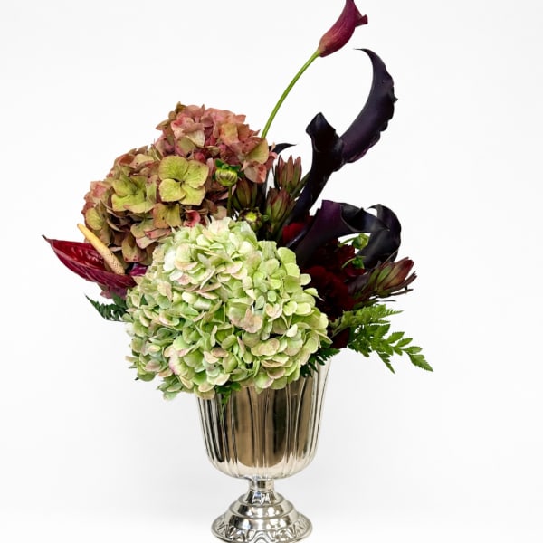 Hydrangea arrangement with dark calla lilies in a glass vase
