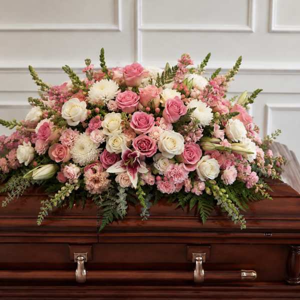 Pink and white floral spray on a wooden casket