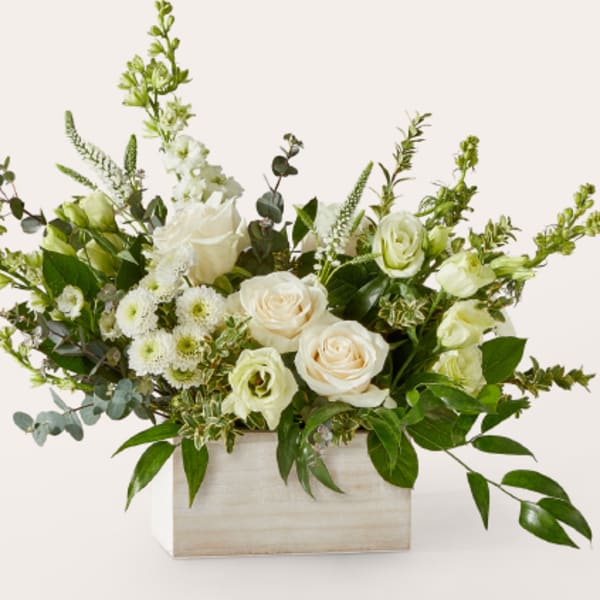 White roses and pale green flowers in a wooden box
