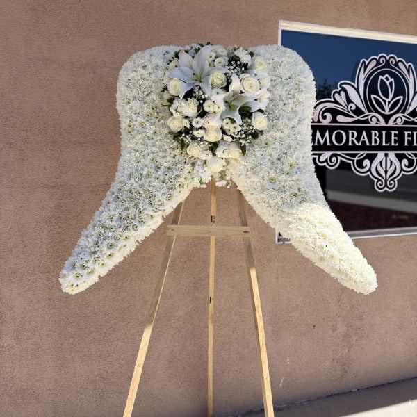 White floral standing spray on a wooden easel with roses and lilies