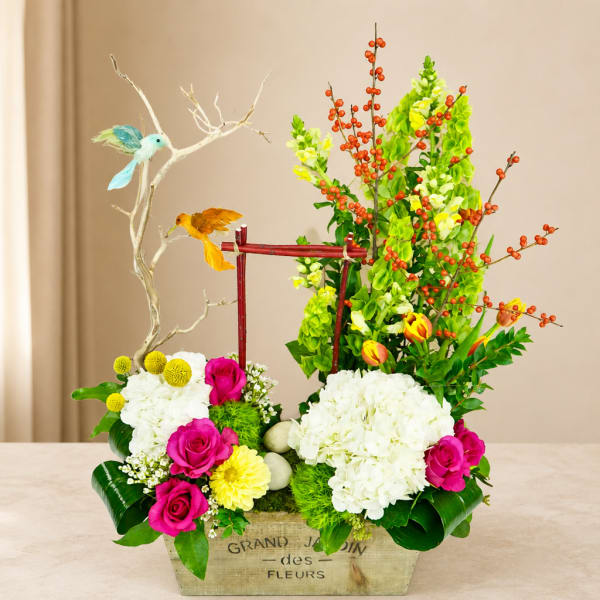 Colorful floral arrangement in a wooden box with birds and branches