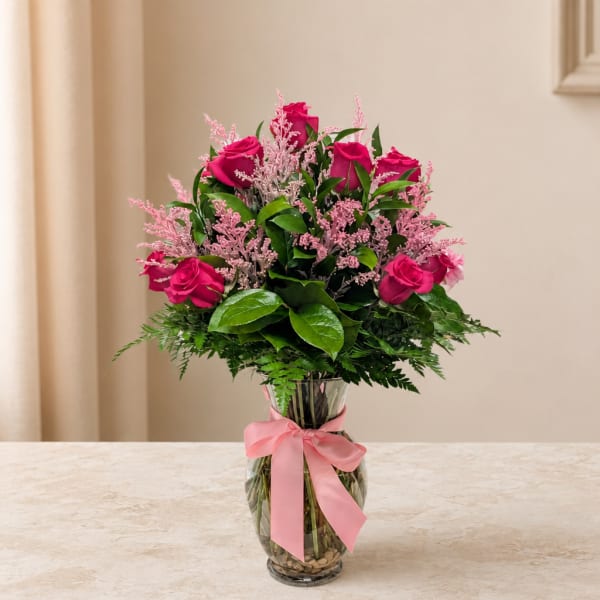 Pink roses in a clear glass vase with a pink ribbon