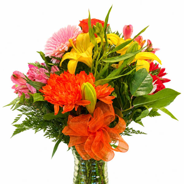 Mixed bouquet of yellow lilies, pink and orange flowers in a glass vase