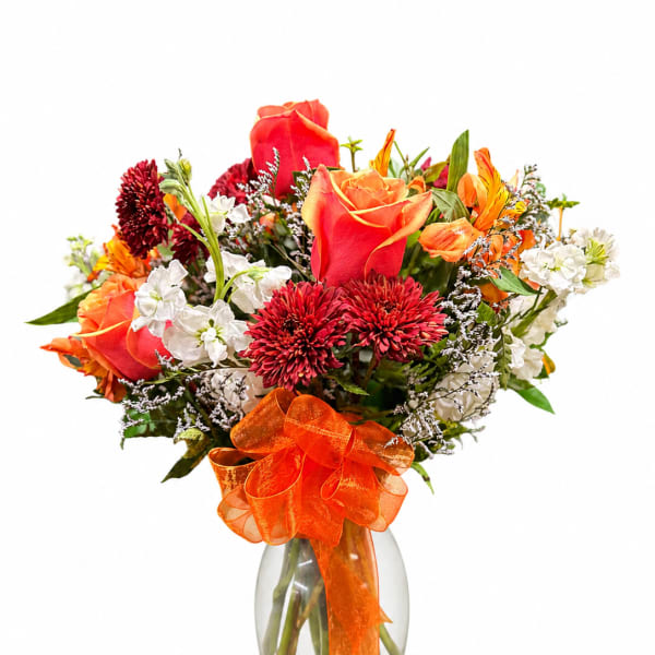 Bouquet of red and orange roses with white flowers in a glass vase
