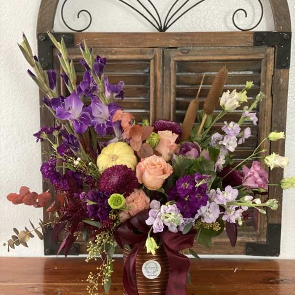 Mixed bouquet in a ribbed vase with purple, peach, and lavender flowers