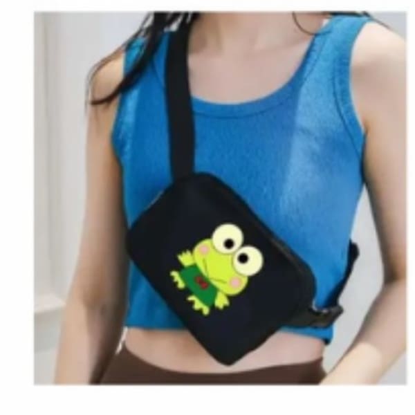 Person wearing a black crossbody bag with a cartoon frog graphic