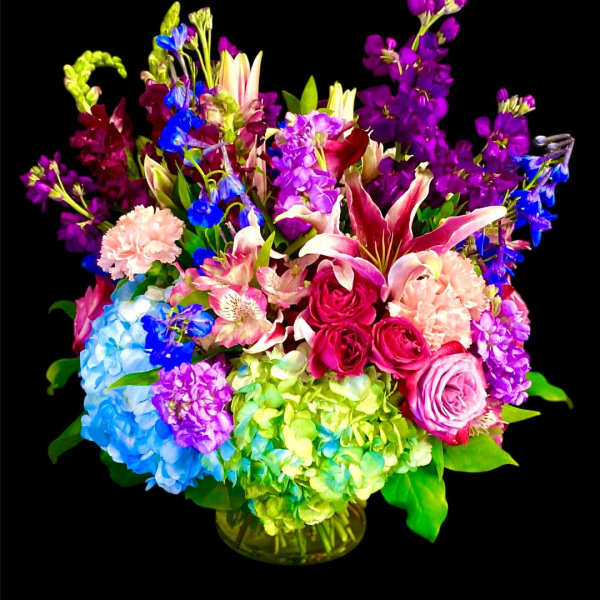 Colorful mixed bouquet in a glass vase with hydrangeas, roses, lilies, and stock