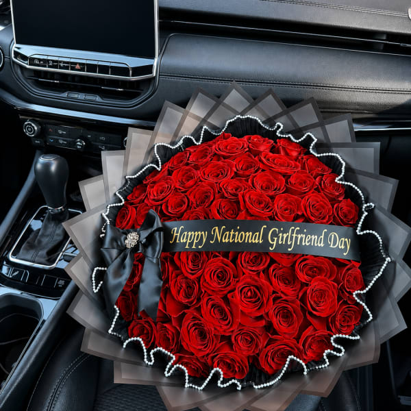 Large bouquet of red roses with a black ribbon and gift banner in a car seat