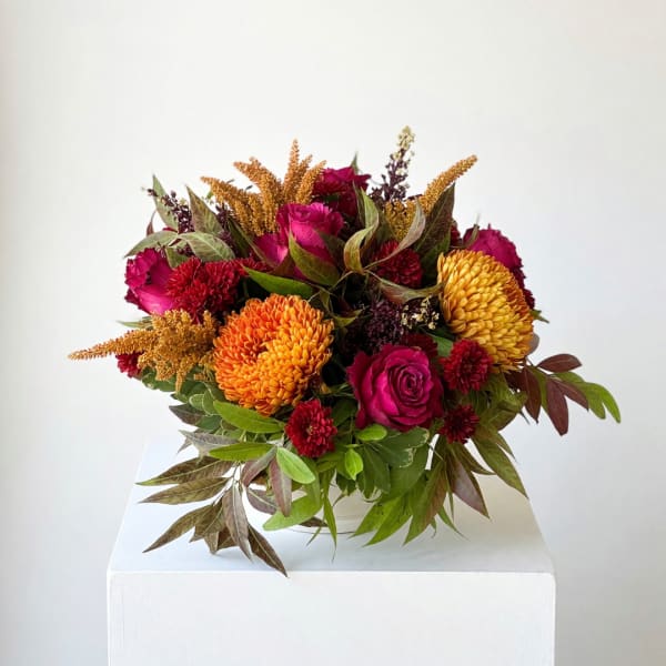 Bouquet of magenta roses and orange chrysanthemums with autumn foliage
