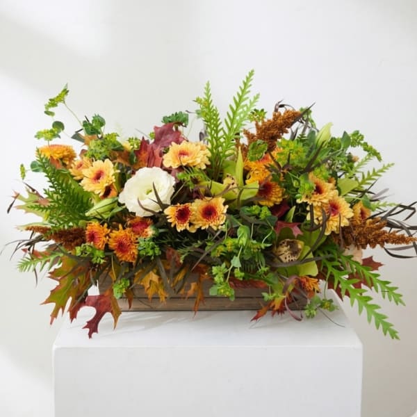 Autumn floral arrangement with yellow daisies in a wooden box