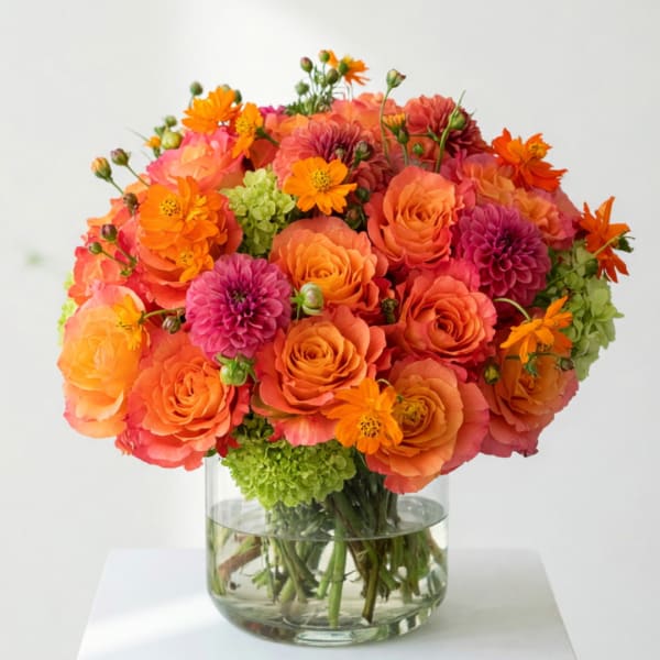Orange and pink flower bouquet in a clear glass vase
