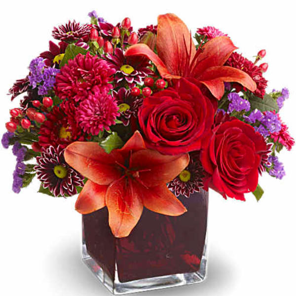 Red and orange mixed flower arrangement in a square glass vase