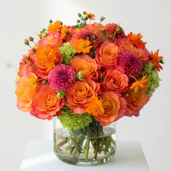 Orange and pink flower bouquet in a clear glass vase