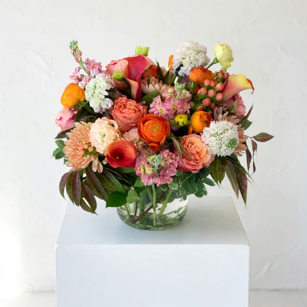 Mixed bouquet in a clear glass vase with pink, orange, and white blooms
