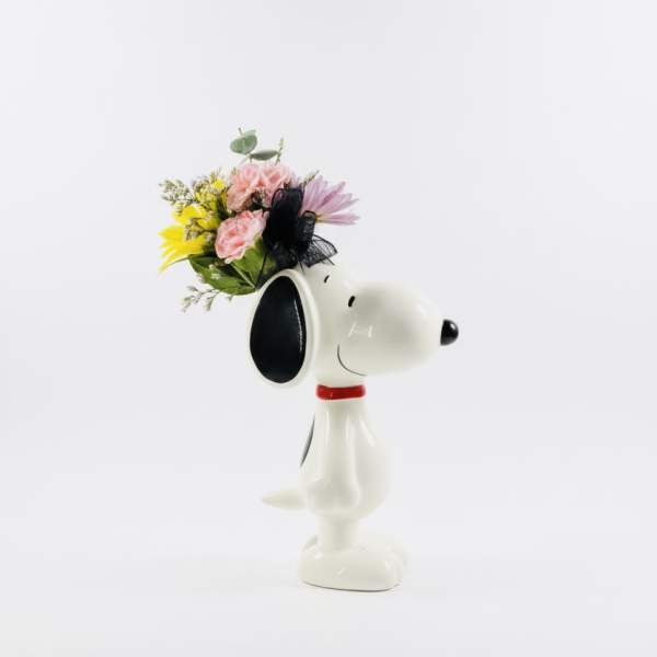 Snoopy figurine holding a small bouquet of pink and yellow flowers