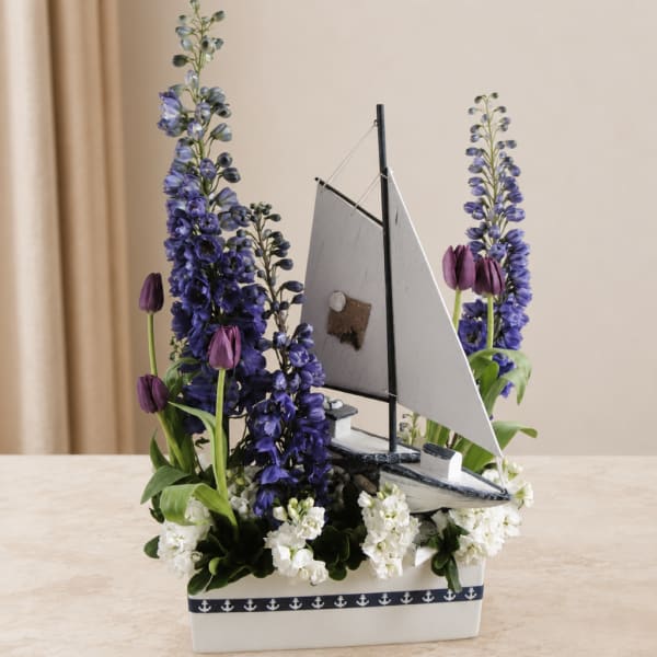 Sailboat centerpiece with purple flowers and white blooms in a white container