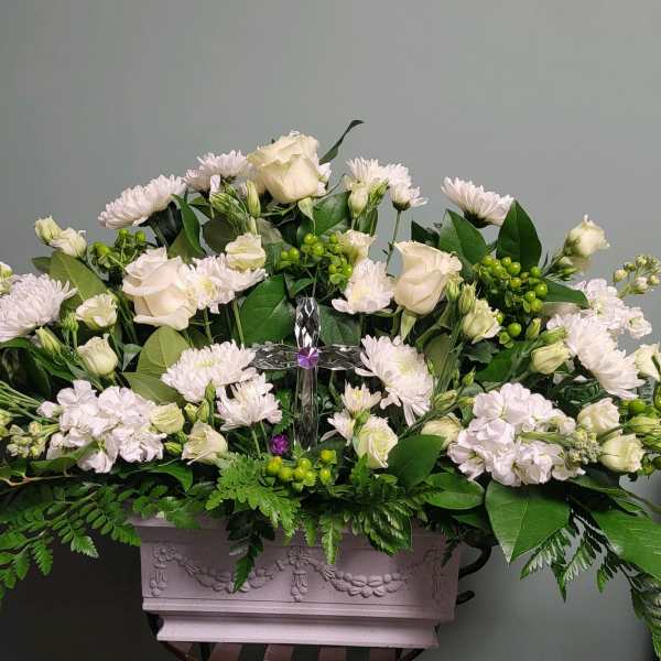 White floral arrangement in a decorative rectangular planter with a clear cross centerpiece