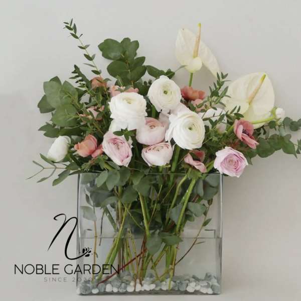 Pink and white flowers arranged in a clear square vase