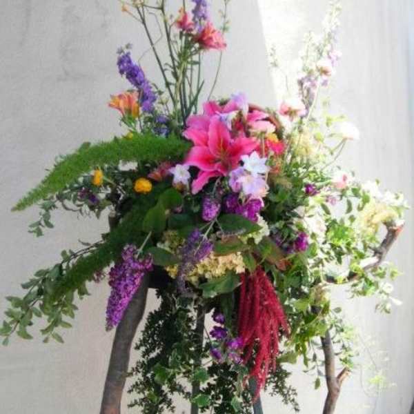 Tall floral arrangement with pink lilies and purple blooms on a stand