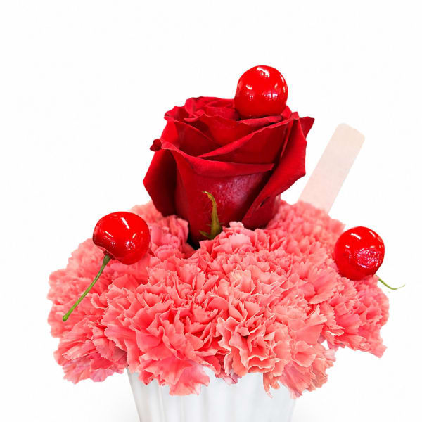Pink carnations in a white cup with a red rose and cherries