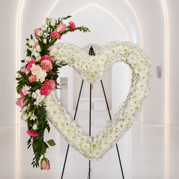 Heart-shaped floral wreath with white and pink flowers on a stand