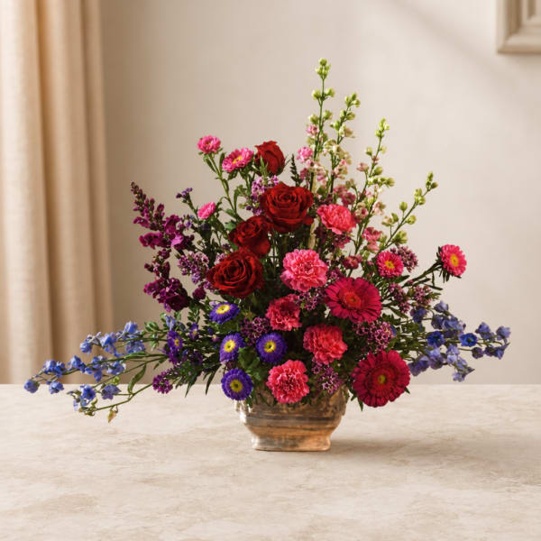 Mixed bouquet of red, pink, purple, and blue flowers in a glass vase