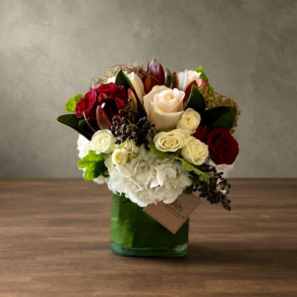 Bouquet of red and white roses in a green glass vase