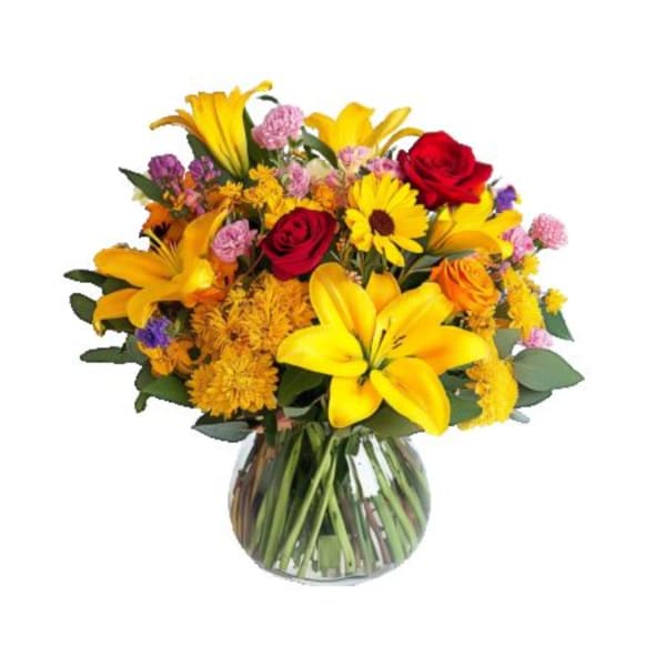Mixed bouquet of yellow lilies, red roses, and daisies in a glass vase