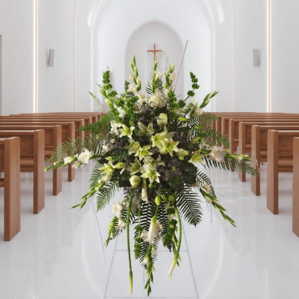 Tall white and green floral arrangement in a church aisle