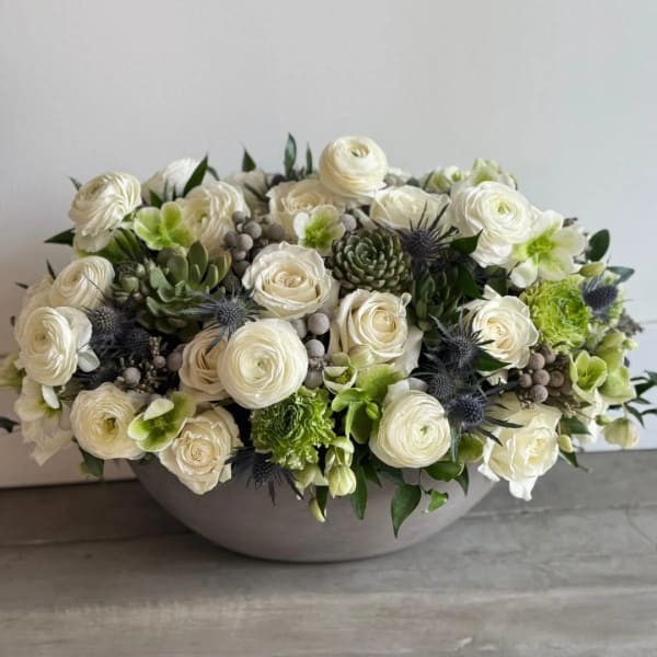 White roses and green succulents arranged in a low gray bowl