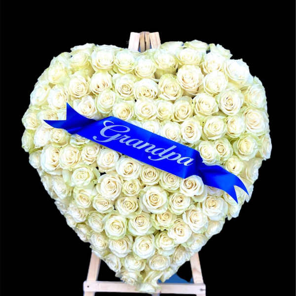 Heart-shaped bouquet of white roses with a blue ribbon on an easel