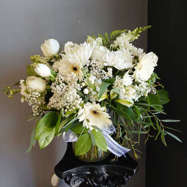 White mixed bouquet in a glass vase with gerbera daisies and tulips