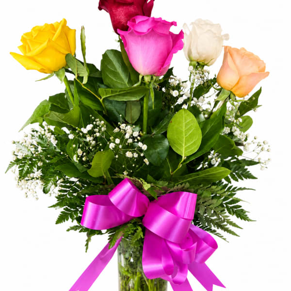 Bouquet of multicolored roses in a glass vase with a pink ribbon