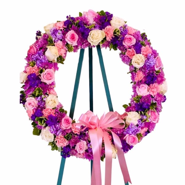 Circular floral wreath on an easel with pink, purple, and white flowers