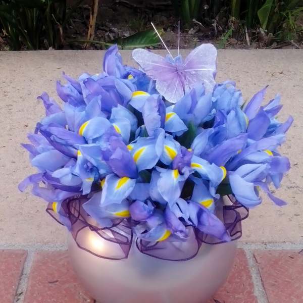 Purple iris bouquet in a round vase with a sheer ribbon and butterfly decoration