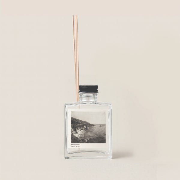 Clear reed diffuser bottle with black cap and wooden reeds