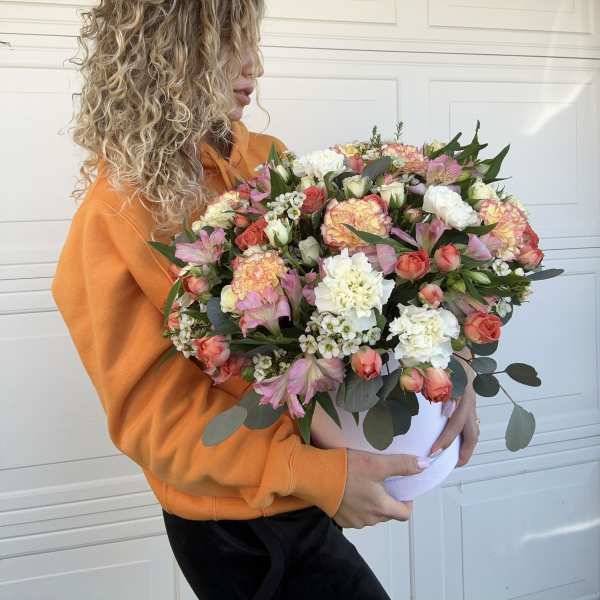 Large mixed bouquet in a white hatbox held by a woman