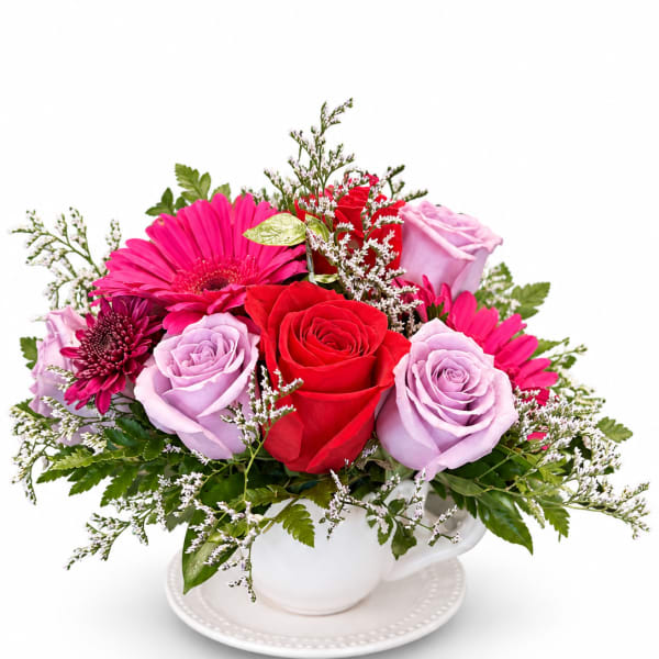 Mixed bouquet of roses and gerbera daisies in a white teacup vase
