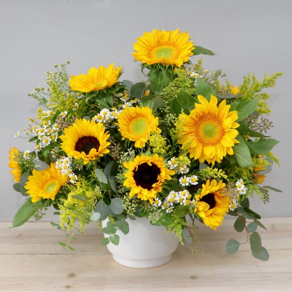 Bouquet of yellow sunflowers and small white daisies in a white vase