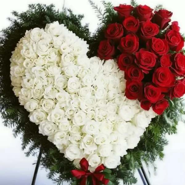 Heart-shaped standing arrangement of red and white roses with a red ribbon