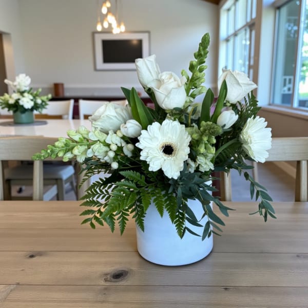 White roses and gerbera daisies arranged in a white vase