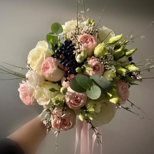 Handheld bouquet of blush and white roses with green buds and ribbon