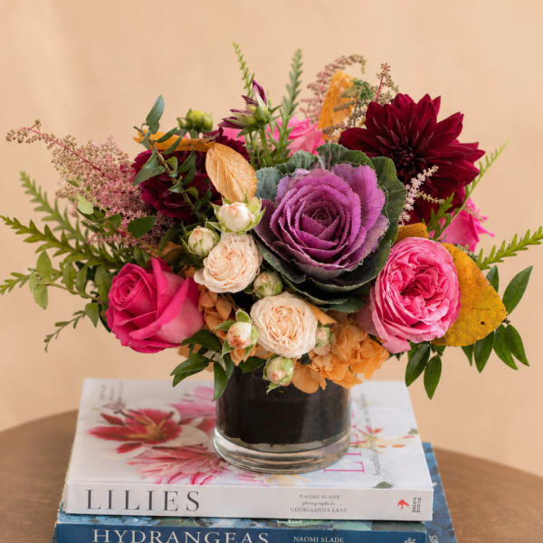 Mixed bouquet of roses, dahlias, and ornamental cabbage in a glass vase